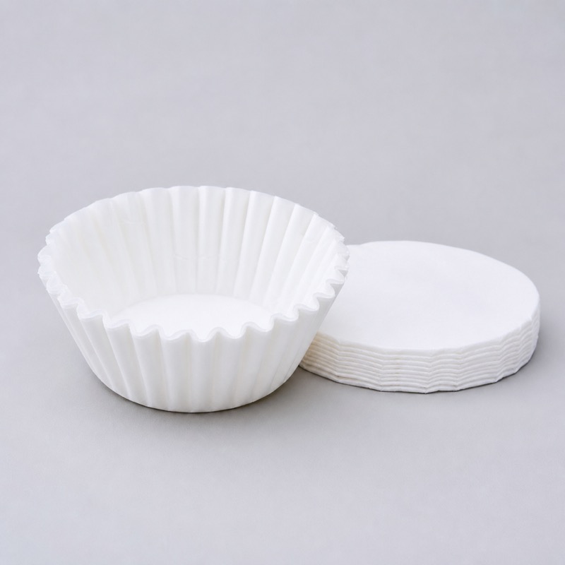 Round white flat-bottom paper filter standing open next to a flat stack of the same filters