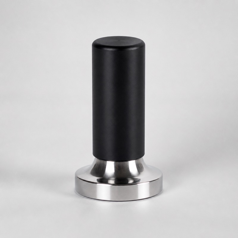 Espresso tamper with a black handle and a flat steel base, standing upright