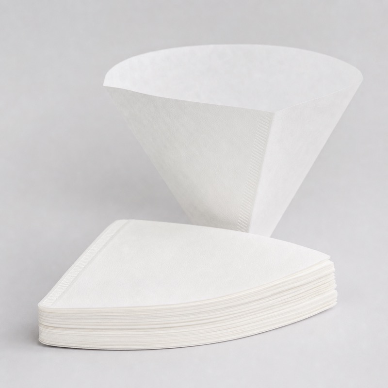 Stack of white cone-shaped paper coffee filters with one standing open behind them