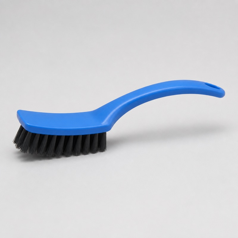 Brush with a curved blue handle and short angled black bristles, lying on its side